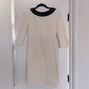 Ivory dress with black stone neck line, zipper in the back. Knee length.
